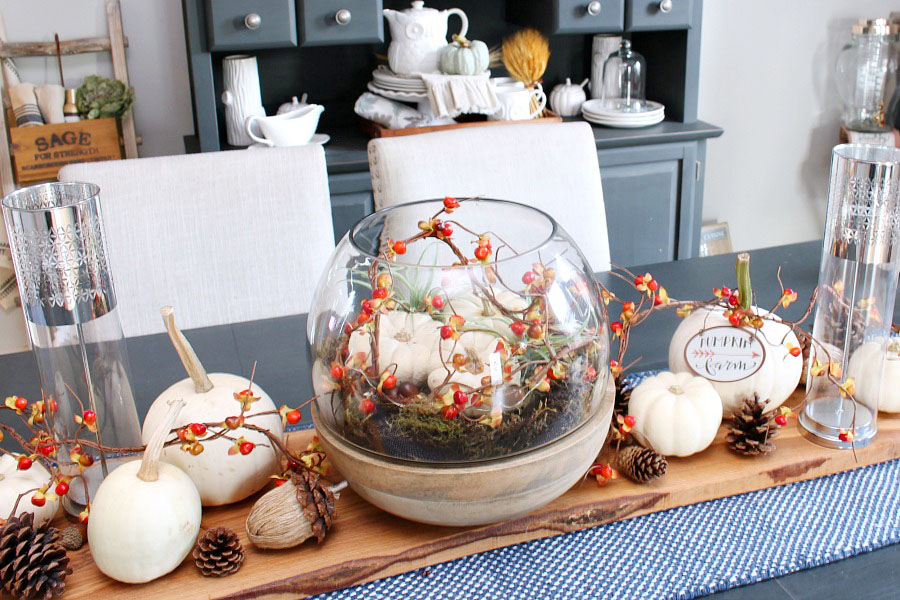 A terrarium with white mini pumpkins and fairy lights