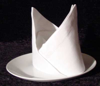 Bishops Hat Napkin Fold on a white plate with black background