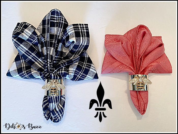 Two Fleur-de-lis napkin folds using a black and white check napkin and a red napkin, held in a napkin ring