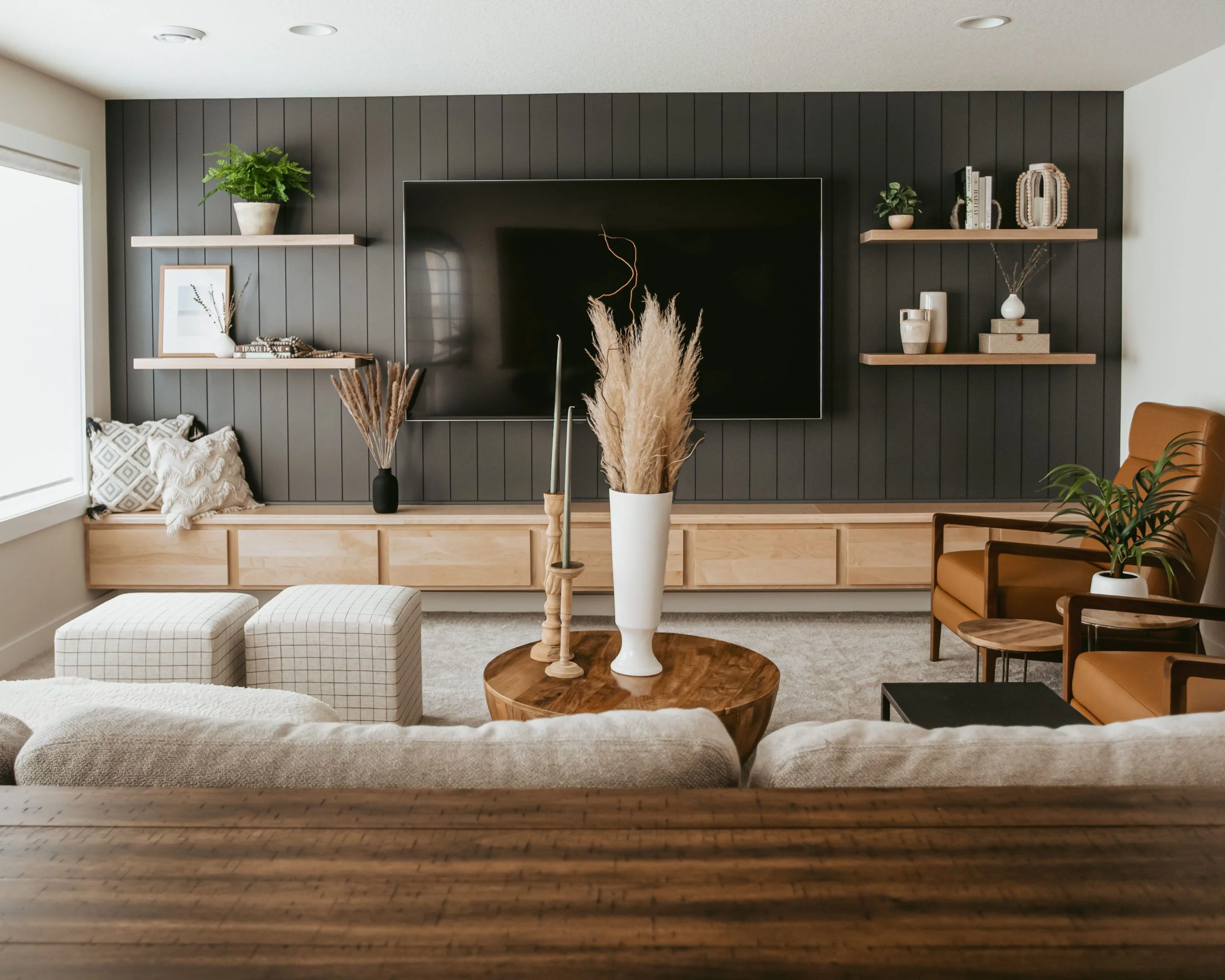 Modern rustic living-room with black wood panel accent wall and floating shelves