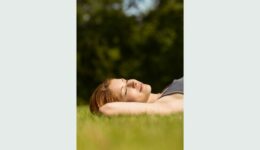 Text: self-care without guilt. Colourmyliving.com Image of a red-haired girl lying on the grass with her hands behind her head